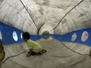 Child looking out a peephole from inside a large toy