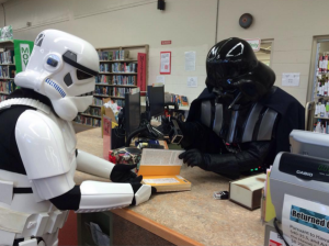 People dressed in star wars costumes checking out a book