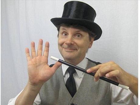 A man holding a black and white magic wand with top hat