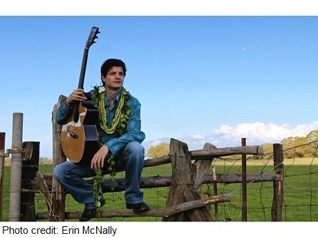 Musician Jeff Peterson sitting on a fence