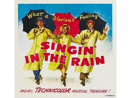 Singing' in the Rain Musical Cover: three people in raincoats and umbrellas smiling in the rain