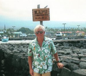 Man posing in front of sign that says 'Kapu' in front of a rock wall