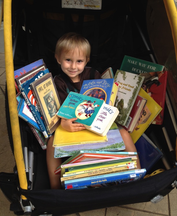 Child in stroller holding lots of books