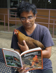 Man holding a chicken and reading a book