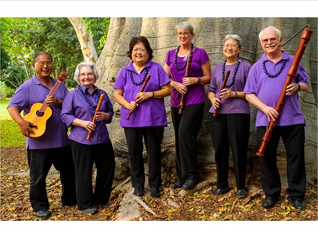 Group of 6 people standing in front of a tree. Five people are holding recorders. One person is holding a 'ukelele.
