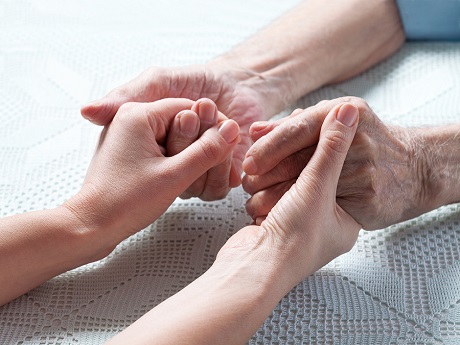Caregiver holding hands with elder patient.