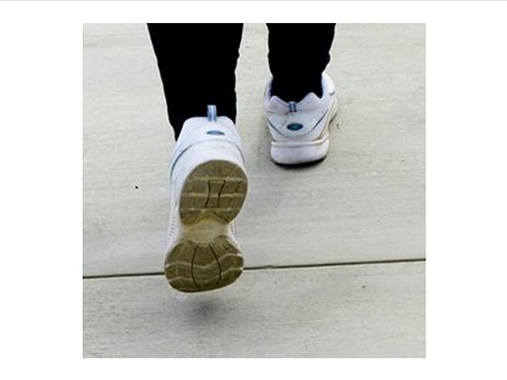 Photo of pair of walking shoe-clad feet with right foot forward and left heel raised.
