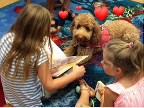 Girls reading to dog with hearts