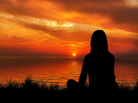 Woman meditating near sunset