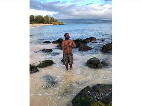 man in prayer pose standing in ocean