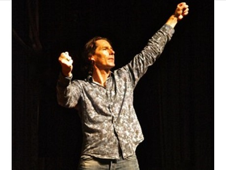 Man holding arms above his head, on a stage