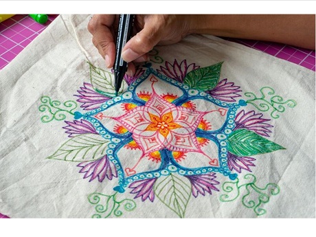 Artist drawing a colorful Mandala on a reusable bag