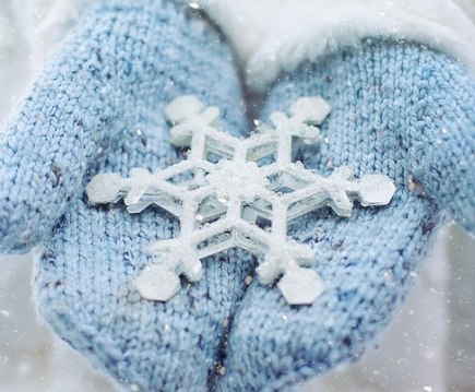 Blue mittens holding a large snowflake