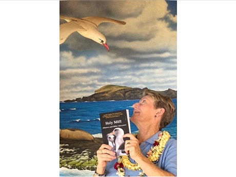 Woman looking up at an albatross while holding a book