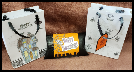 two Halloween themed favor bags with black stamps saying Happy Halloween and Trick or Treat with one haunted house, one black tube with orange Happy Haunting decoration