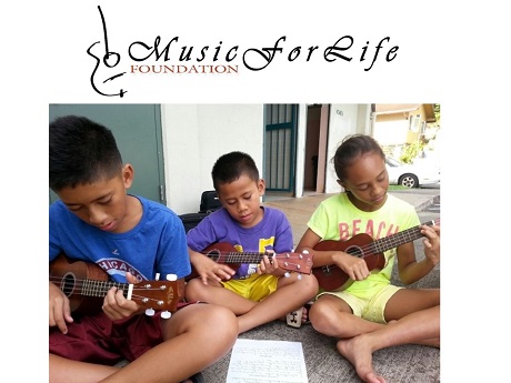 Three children sitting and playing the ukulele