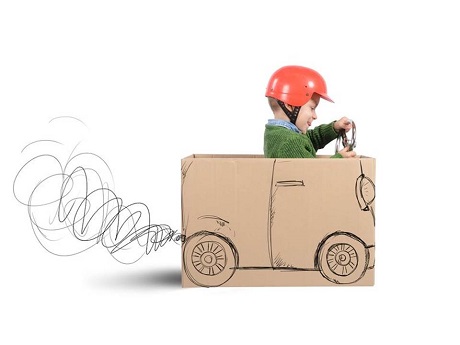 boy pretending to drive a cardboard box car