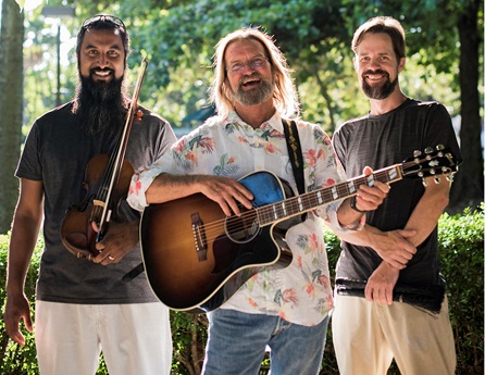 Girish Varma, Wayne Watkins, and Jason Pfahl make up the Howling Dogs, one holding a guitar, one holding a violin and the third standing arms held with drumsticks