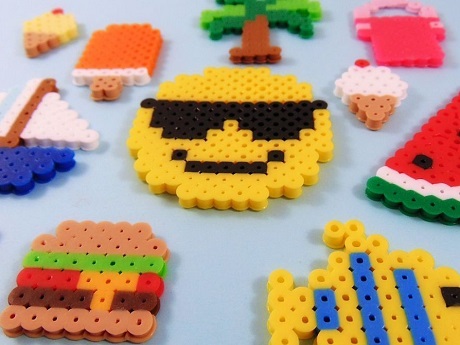 several perler bead designs to include: a hamburger, sailboat, ice cream, palm tree, smiley face, fish, and water melon
