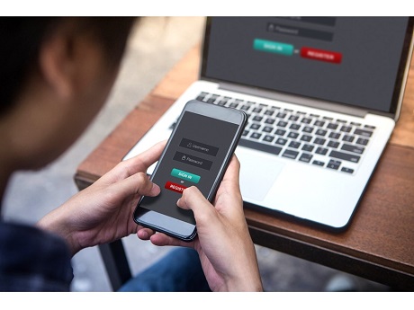 Man holding smartphone with laptop on table