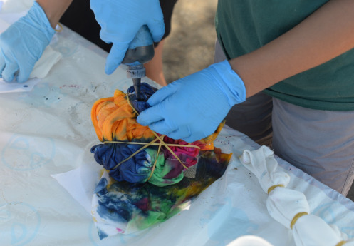 hands adding dye to colorful fabric