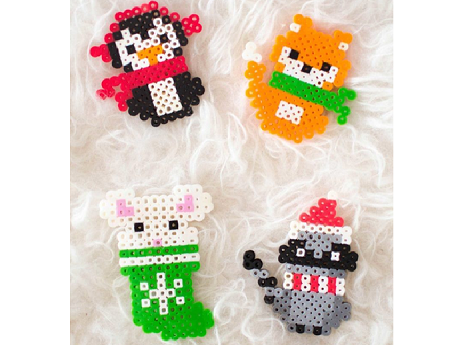 Total of four perler bead creations. One penguin with red earmuffs, one fox with a green scarf, one mouse inside a green stocking, and a racoon with a santa hat and white and red scarf
