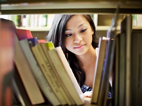 Female Teen looking at books in library