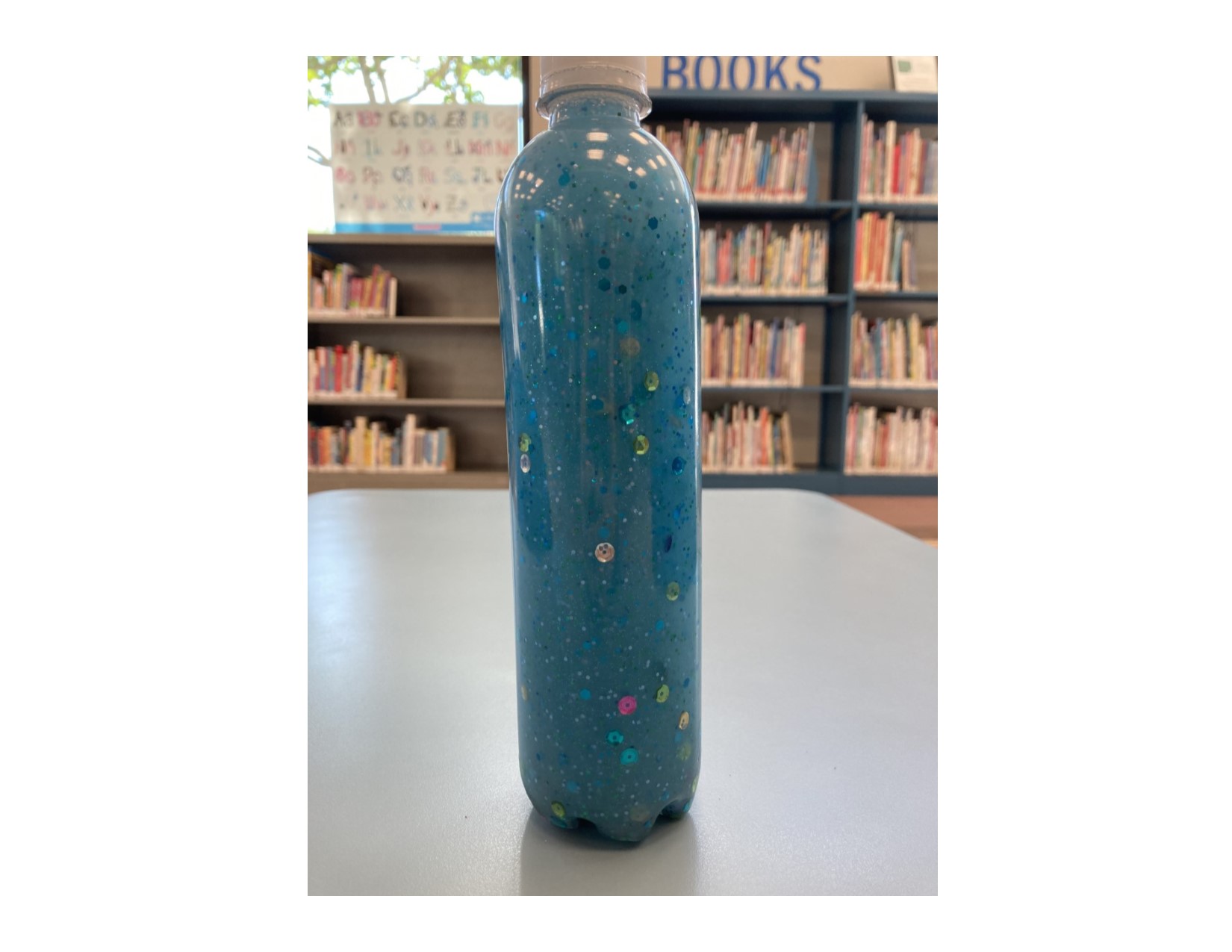 blue glitter calming bottle in the library