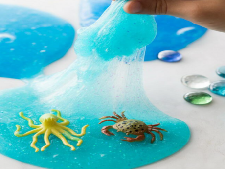 Blue slime containing a plastic, yellow octopus toy and a plastic crab toy.