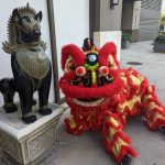 red and gold Chinese lion dancing lion sitting down by a statue
