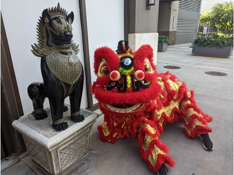 red and gold Chinese lion dancing lion sitting down by a statue