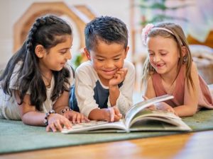 Two girls and a boy reading a book together