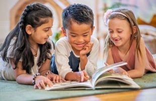 Two girls and a boy reading a book together