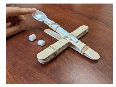 Marshmallow catapult made from popsicle sticks, rubber bands, and a plastic spoon.