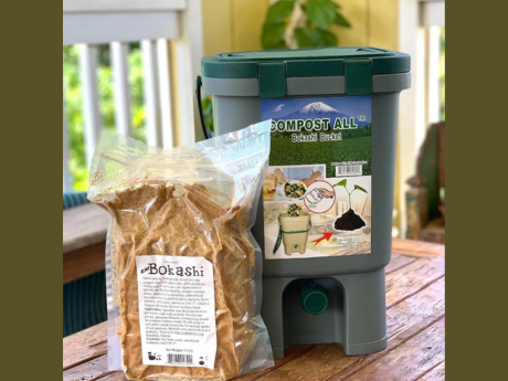 Bokashi compost in a bag, in front of a composting bin