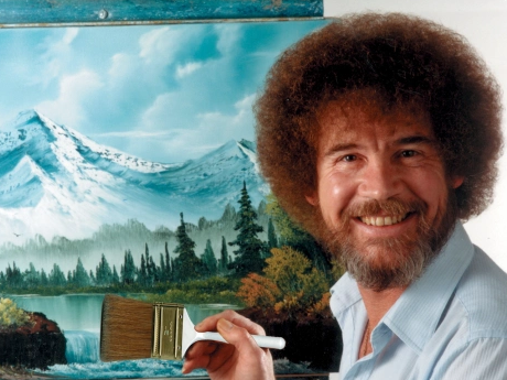 Painter Bob Ross in front of one of his landscape paintings.