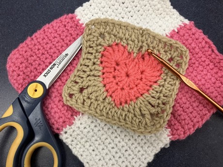 heart granny square on top crochet project with scissors and hook