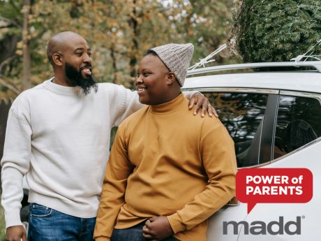 Father and son smiling and leaning against a car. MADD Power of Parents logo.