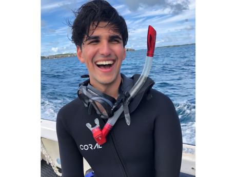 Man wearing a wetsuit and snorkel, smiling broadly at the camera