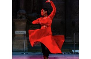 An Indian woman dancing with red overhead lighting