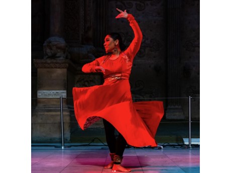 An Indian woman dancing with red overhead lighting
