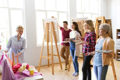 Four art students studying a still life that the teacher is pointing at.