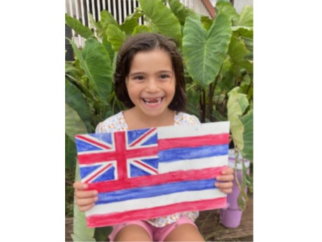 smiling girl holding a watercolor painted Hawaiian flag,