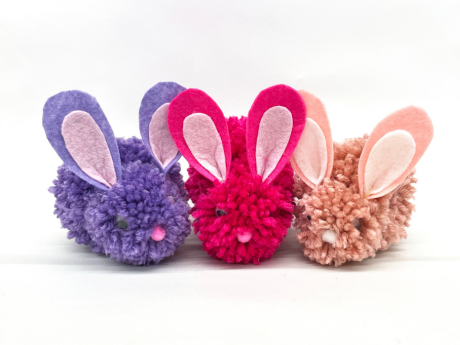 Three pompom bunnies. One is purple, one is pink, and the other is salmon colored.