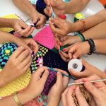 group of hands and people knitting crocheting and materials