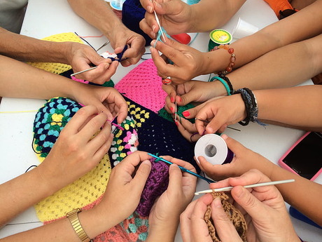 group of hands and people knitting crocheting and materials