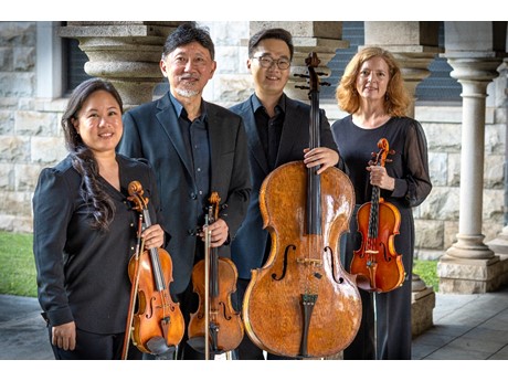 4 musicians holding string instruments standing side by side