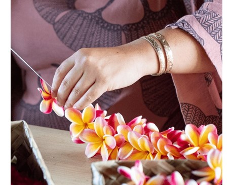 Woman stringing a plumeria lei