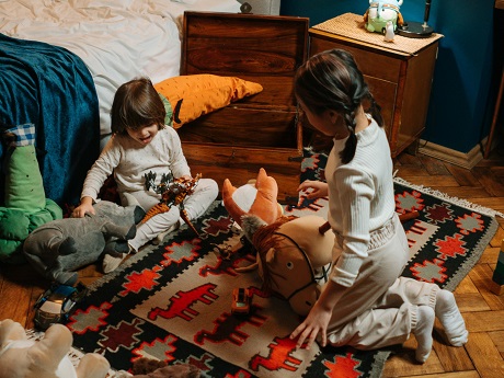 Two children wearing pajamas play with toys on the floor.