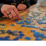 Hands putting together a blue colored puzzle